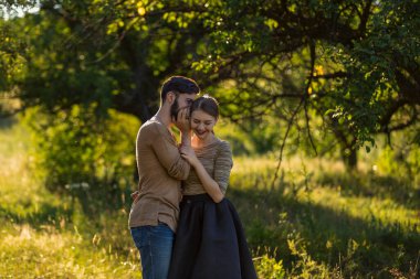 man tells in his ear the secret of his girlfriend walking in the park