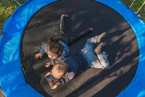 Barn Tittar Telefonen När Ligger Studsmatta Ovanifrån — Stockfoto