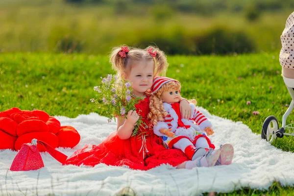 女孩抱着洋娃娃坐在毛毯上 — 图库照片