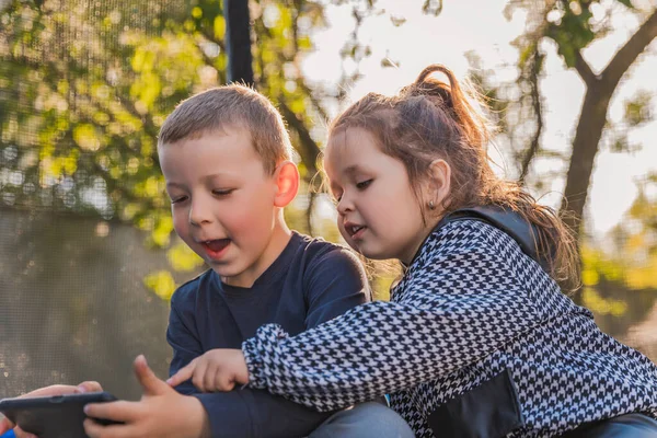 Retrato Crianças Que Sentam Trampolim Olham Para Telefone — Fotografia de Stock