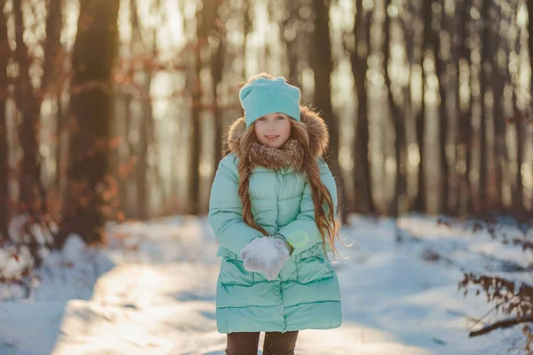 太陽に照らされた冬の森を背景にした少女の肖像画 — ストック写真