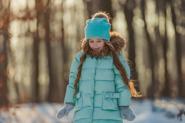 太陽に照らされた冬の森を背景にした少女の肖像画 — ストック写真