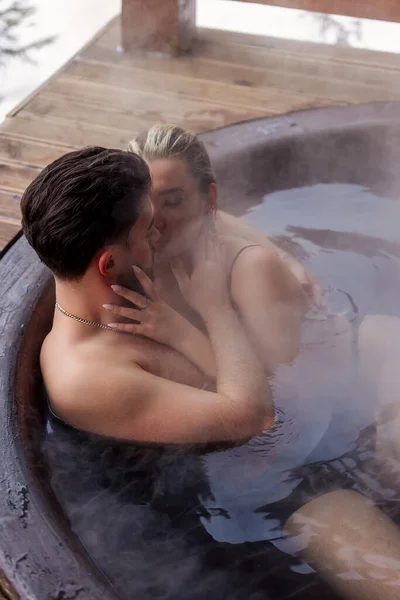 年轻夫妇坐在一个大浴缸里时拥抱在一起 — 图库照片