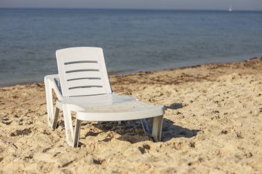Denizin arka planında beyaz plastik şezlong