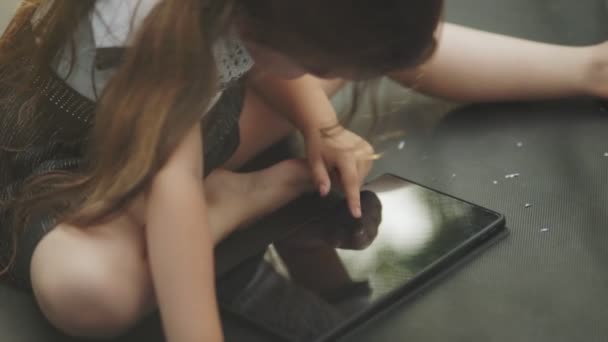 Het Kind Zit Een Trampoline Kijkt Naar Tablet Die Periodiek — Stockvideo