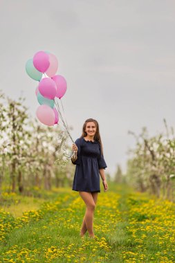 Çiçekli elma bahçeleri olan bir tarlada balonlu kız.