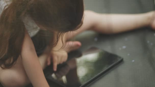 Het Kind Zit Een Trampoline Kijkt Naar Tablet Die Periodiek — Stockvideo