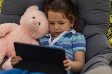 Kız doğada dinlenirken elinde bir tablet tutuyor.