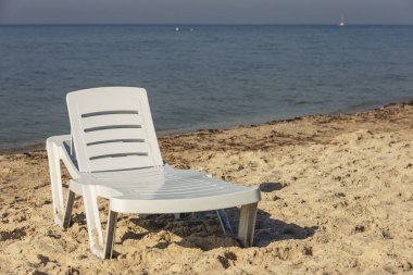 Denizin arka planında beyaz plastik şezlong