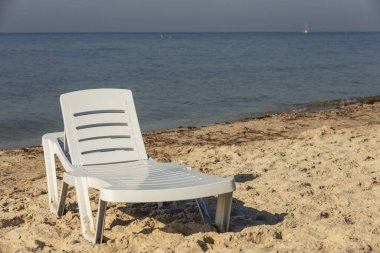 Denizin arka planında beyaz plastik şezlong