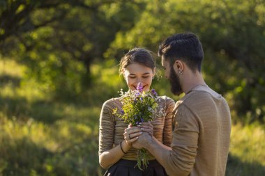 Erkek, kız arkadaşına yabani çiçekler verir.