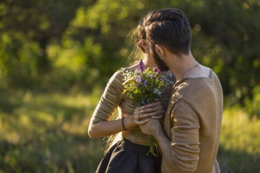 Erkek, kız arkadaşına yabani çiçekler verir.