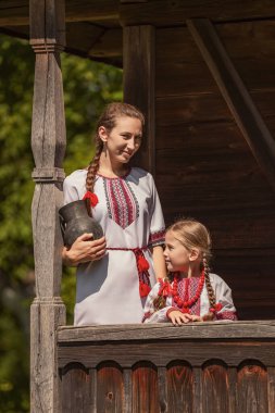 mother and daughter dressed in Ukrainian national costumes look at the camera clipart