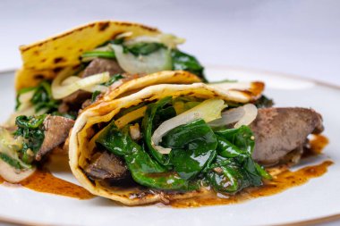 Potato pancakes with goose liver and steamed fresh spinach