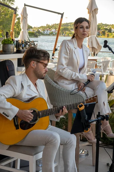 stock image QUINTA DO LAGO, PORTUGAL - 26th JUNE 2022: Band duo singer and guitar player called Beatriz playing in a beach bar restaurant in Quinta do Lago.