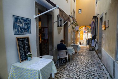 SINTRA, PORTUGAL - 27 Haziran 2022: Restoranlar ve hediyelik eşyalar da dahil olmak üzere Sintra köyünün dar sokakları.