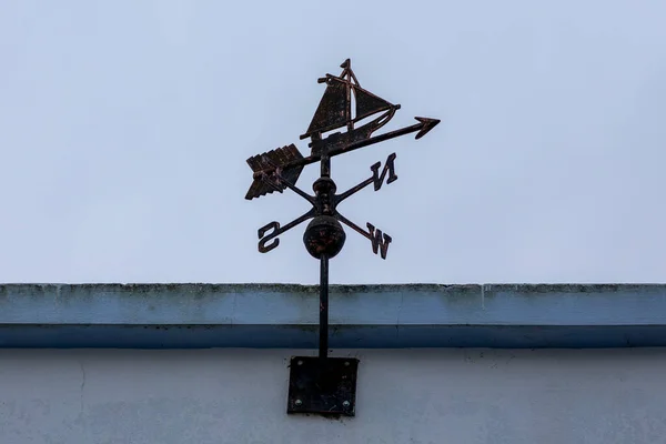 A weather vane (or wind vane, weathercock) on top of a building in a rural area.