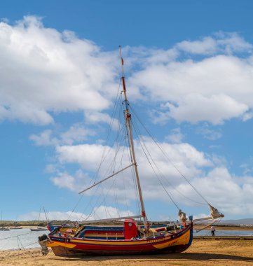 ALVOR, PORTUGAL - 16 Nisan 2023: Güzel Portekiz geleneksel balıkçı teknesi sarı, mavi ve kırmızı boyalı.