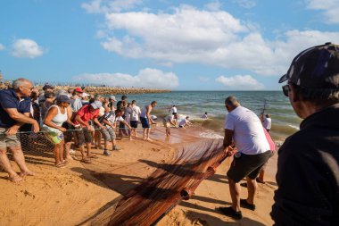 QuARTEIRA, PORTUGAL - 6 HAZİRAN 2023: Plaj kıyısındaki yerel halk tarafından yapılan ağ balıkçılığı geleneği.