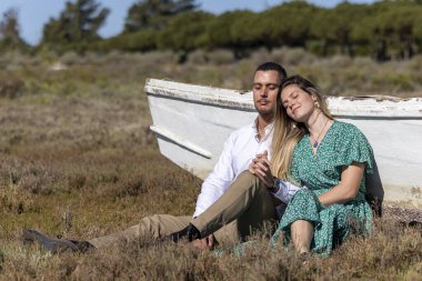 Genç ve mutlu Avrupalı bir çiftin ahşap bir teknenin yanında bir arada durmasını yakından görmek.