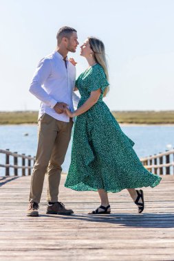 Genç ve mutlu Avrupalı bir çiftin ahşap yolda birbirlerine tutunuşunun yakın görüntüsü.