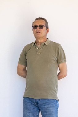 Beyaz arka planda siyah güneş gözlüklü, orta yaşlı beyaz bir adam..