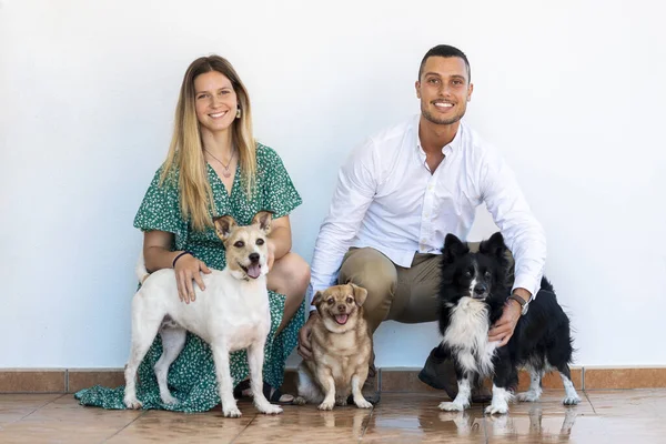 Husband and wife with three puppy dogs over a white background.