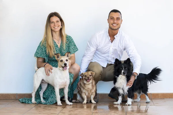 Husband and wife with three puppy dogs over a white background.