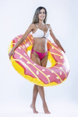 Gri arkaplanı üzerinde şişme yüzme halkası olan bikinili bir kadın..