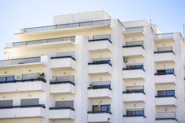 Güneşli bir günde mavi gökyüzü olan yüksek modern bir apartman manzarası.