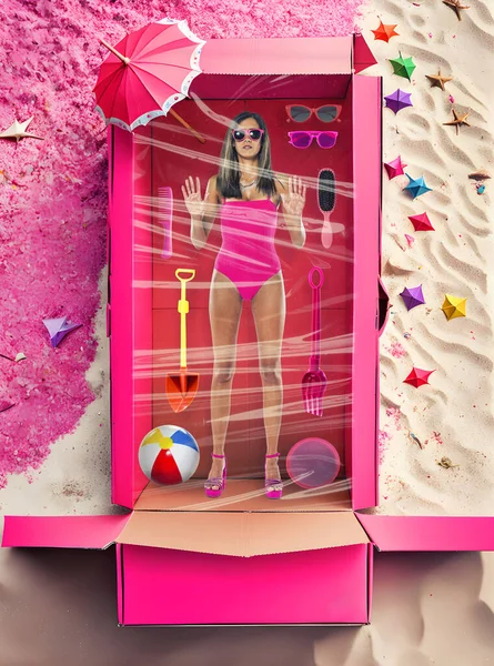 Human size adult woman inside pink card box with several objects related to beach.