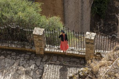 Ronda, İspanya - 20 Ekim 2023: İspanya 'nın Endülüs bölgesinde bulunan çok sayıda turist tarafından ziyaret edilen Ronda köyünün ünlü kemerli köprüsünün yanındaki turist.