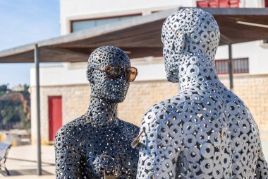 Albufeira şehrinde güneş gözlüğü takan bir adam ve kadının metal tüpler heykeli.