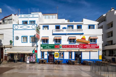 ALBUFEIRA, PORTUGAL - 9 Kasım 2024: İş yerleri ve tipik dar sokakların yer aldığı Albufeira şehrinde güneşli bir gün.