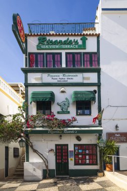 ALBUFEIRA, PORTUGAL - 9 Kasım 2024: İş yerleri ve tipik dar sokakların yer aldığı Albufeira şehrinde güneşli bir gün.