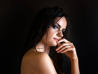 Siyah arka planda ıslak saçlarla poz veren genç, sinirli kadınlar..