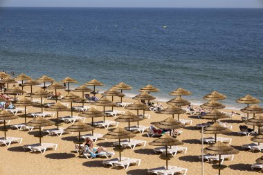 ALBUFEIRA, PORTUGAL - 7 Mayıs 2024: Portekiz 'in Albufeira plajındaki çatı şemsiyeleri ve şezlonglar.
