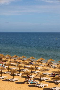 ALBUFEIRA, PORTUGAL - 7 Mayıs 2024: Portekiz 'in Albufeira plajındaki çatı şemsiyeleri ve şezlonglar.