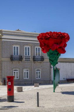 View of the renovated Sao Bras de Alportel main plaza with large red carnation flower , located in Portugal. clipart