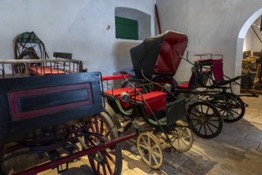 SAO BRAS DE ALPORTEL, PORTUGAL - 6th MAY 2024: Close view of several types of coaches and carriages in a well preserved exhibit. clipart