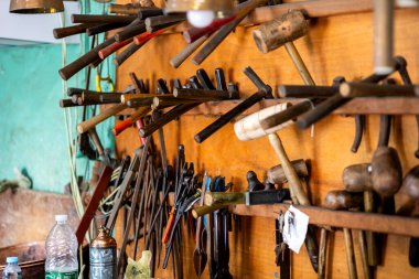 Bir duvarda çekiç, anahtar ve diğer objeleri içeren çeşitli atölye araçları.