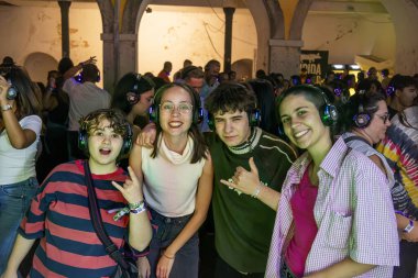 FARO, PORTUGAL: 5th SEPTEMBER, 2024 - Audience enjoying music in headphones on Festival F, a silent disco concept. clipart