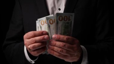 Bir adam siyah arka planda 100 dolar sayar. Yüksek kalite 4k görüntü