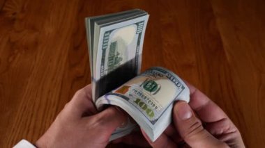 a man hands counts one hundred dollar money on a black background. High quality 4k footage