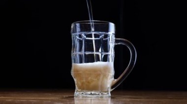  Slow Motion Shot of Pouring Fresh Beer into Glass on Black Background . High quality 4k footage