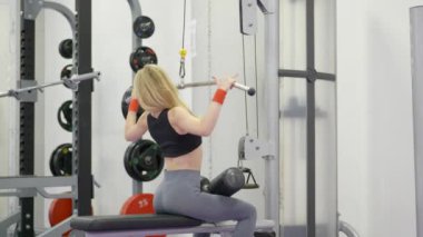 Güzel, sportif genç bir kadın spor salonunda kaslarını çalıştırıyor, spor kıyafetlerini giymiş spor yapıyor.