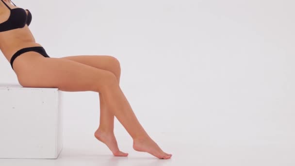 Giovane Bella Donna Incrocia Gambe Pelle Liscia Seduta Sullo Sfondo — Video Stock