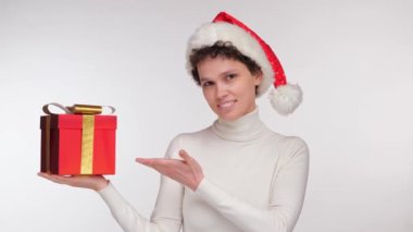 Noel Baba şapkalı mutlu kız elinde beyaz arka planda bir Noel hediyesi tutuyor. Yüksek kalite 4k görüntü