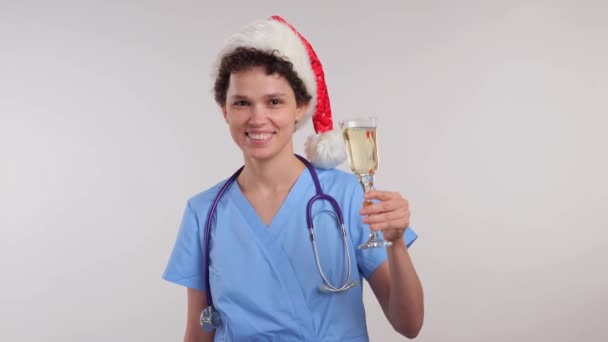 Νοσοκόμα Στο Καπέλο Του Βασίλη Κρατώντας Ένα Ποτήρι Σαμπάνια Χριστούγεννα — Αρχείο Βίντεο