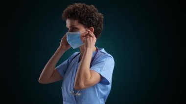 Mutlu Tıp Doktoru bir maske takar ve beyaz bir arka plana gülümser. Yüksek kalite 4k görüntü yavaş çekim
